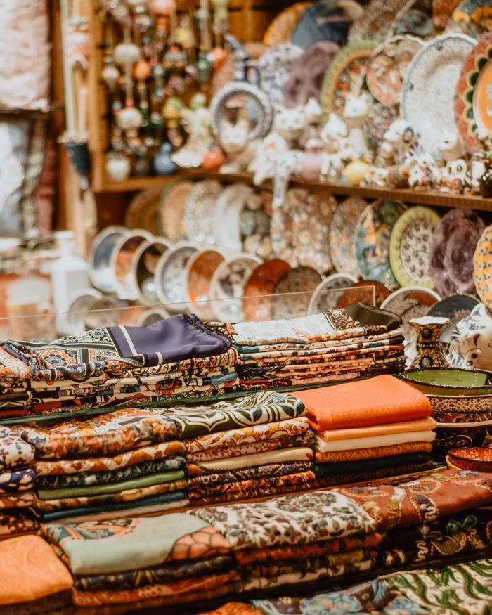 Vibrant display of folded textiles and ornate ceramic plates in a cozy artisan store.
